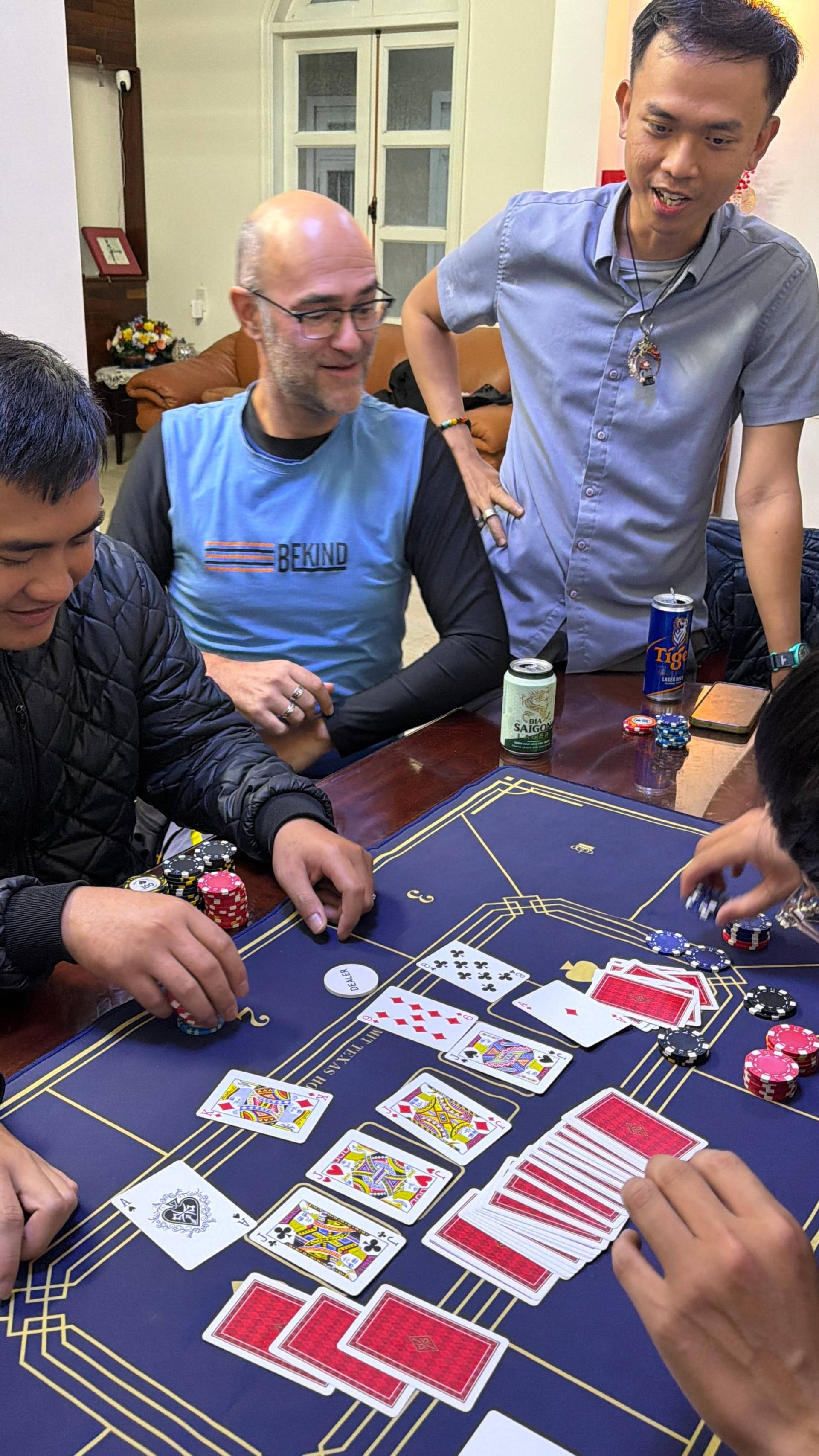 Active card game with players engaged in baccarat, showing dealt cards and poker chips on a professional gaming table during social gaming event in Đà Lạt.