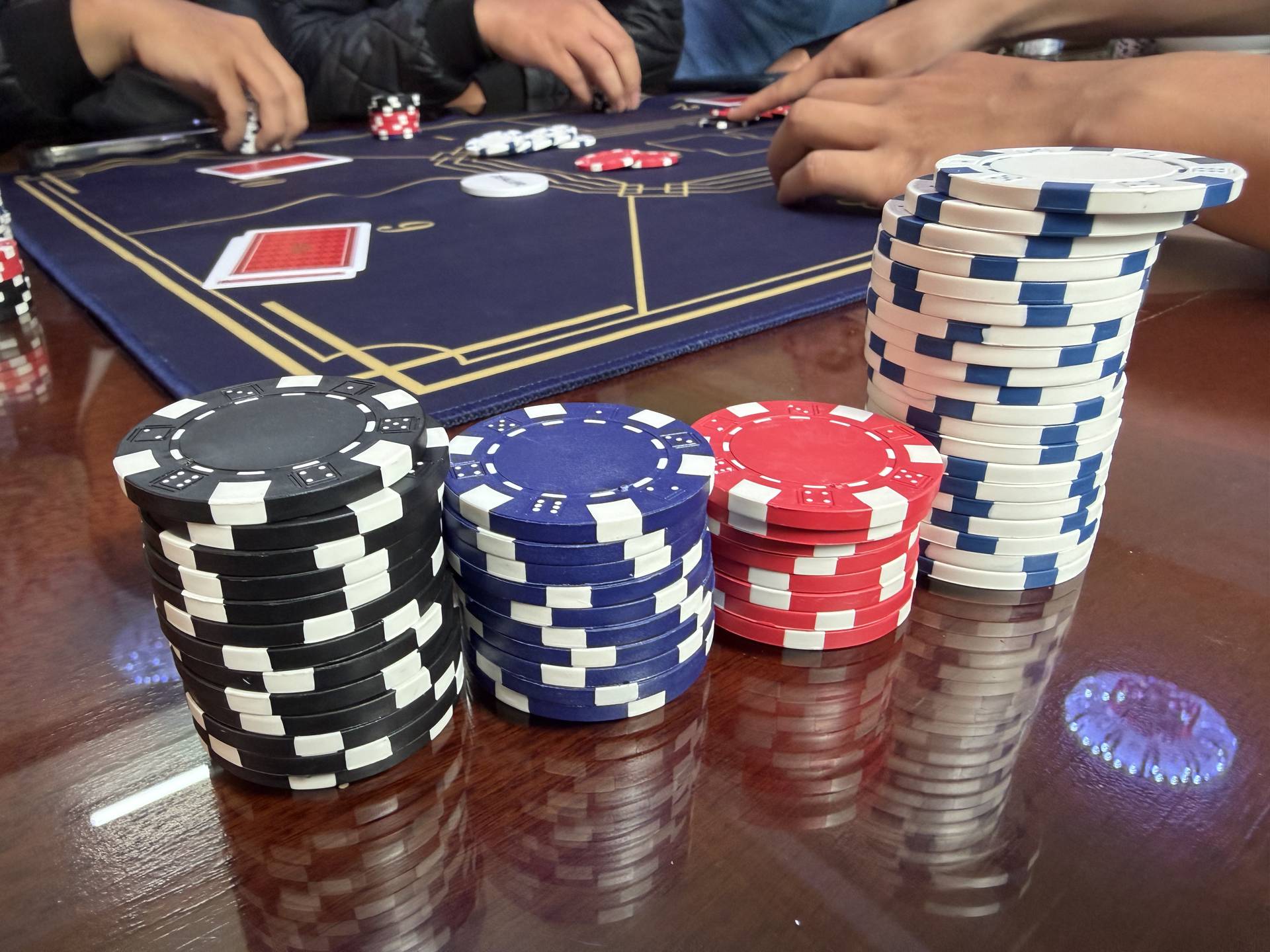 Casino gaming setup featuring organized poker chips in four colors and professional playing cards arranged on a wooden table during an event in Đà Lạt.