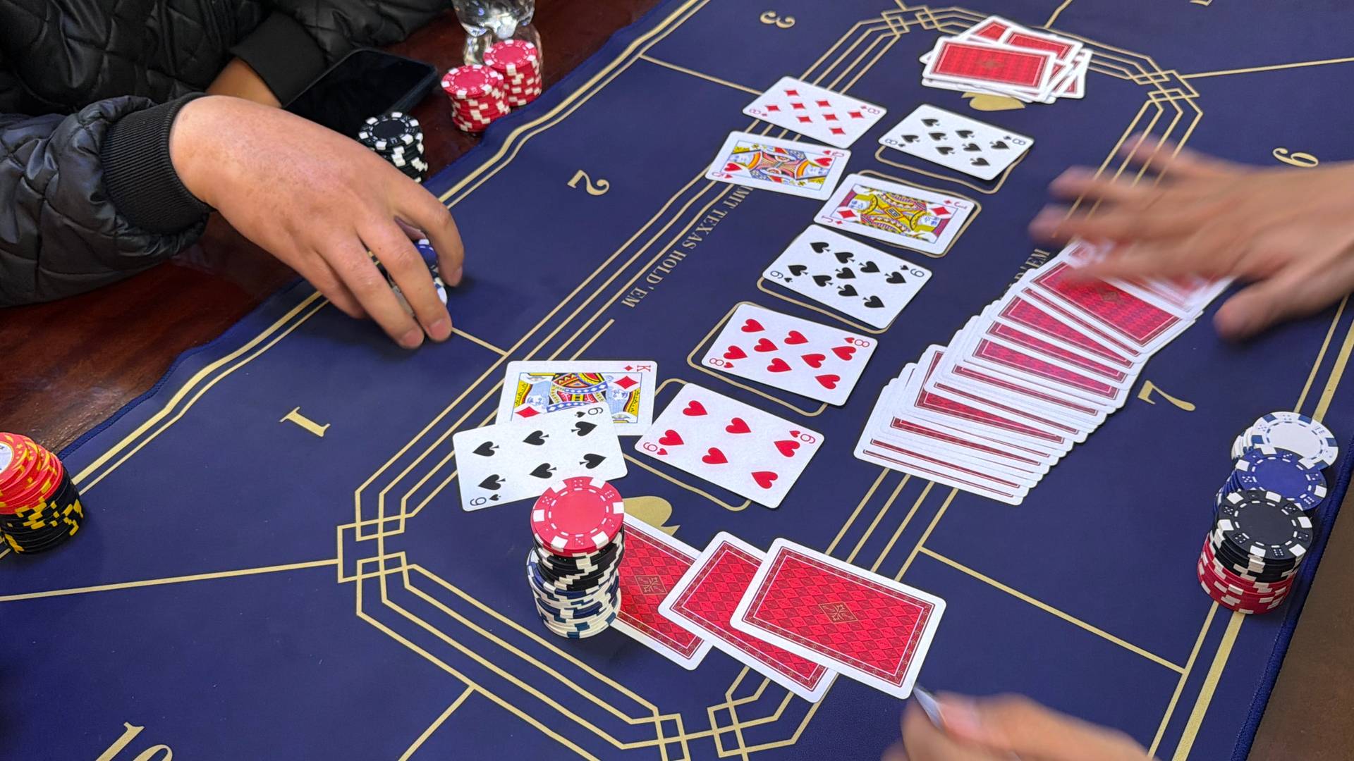Active baccarat card game in progress with stacked poker chips and dealt cards on a professional gaming table, capturing the intensity of social casino gaming in Đà Lạt.