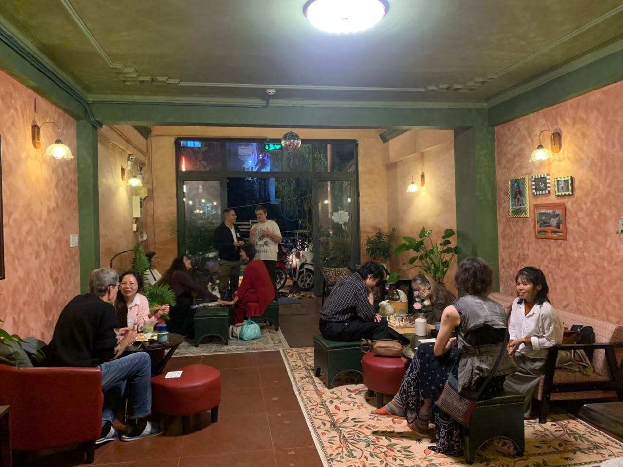 A lively gathering of friends in a cozy café in Đà Lạt, Vietnam, engaging in board games and casual conversation under warm lighting.