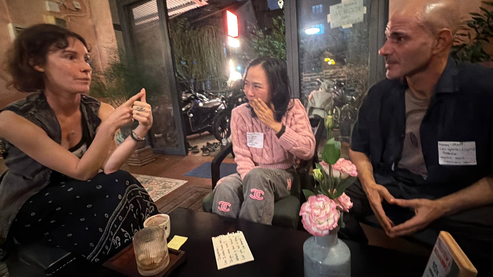 A group of friends engaged in a lively conversation over drinks in a cozy café setting in Đà Lạt, Vietnam.