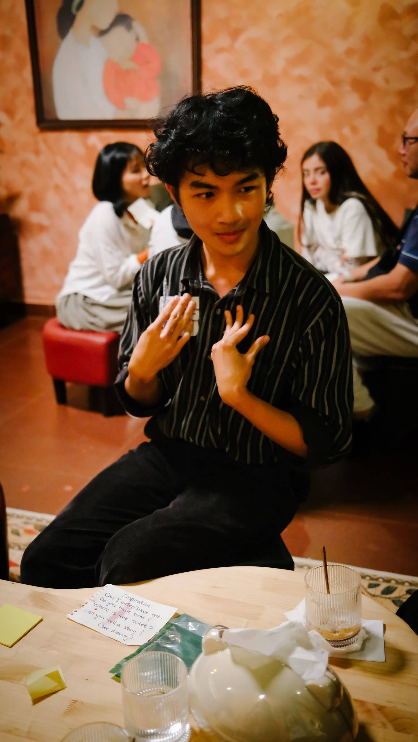 A group of people engaged in a lively discussion around a table in a cozy café setting in Đà Lạt, Vietnam.