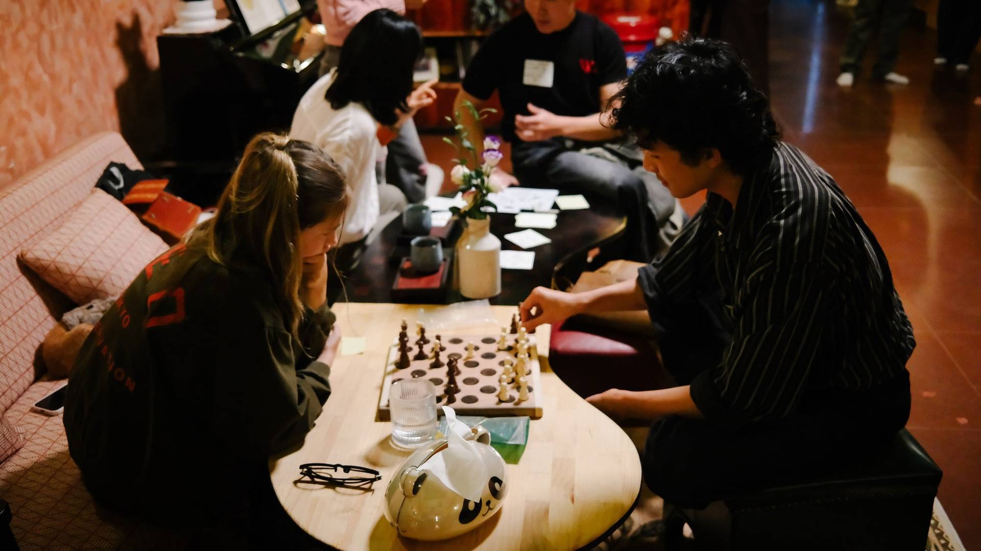 Friends gather in a cozy café in Đà Lạt to enjoy a game of chess over drinks and snacks.