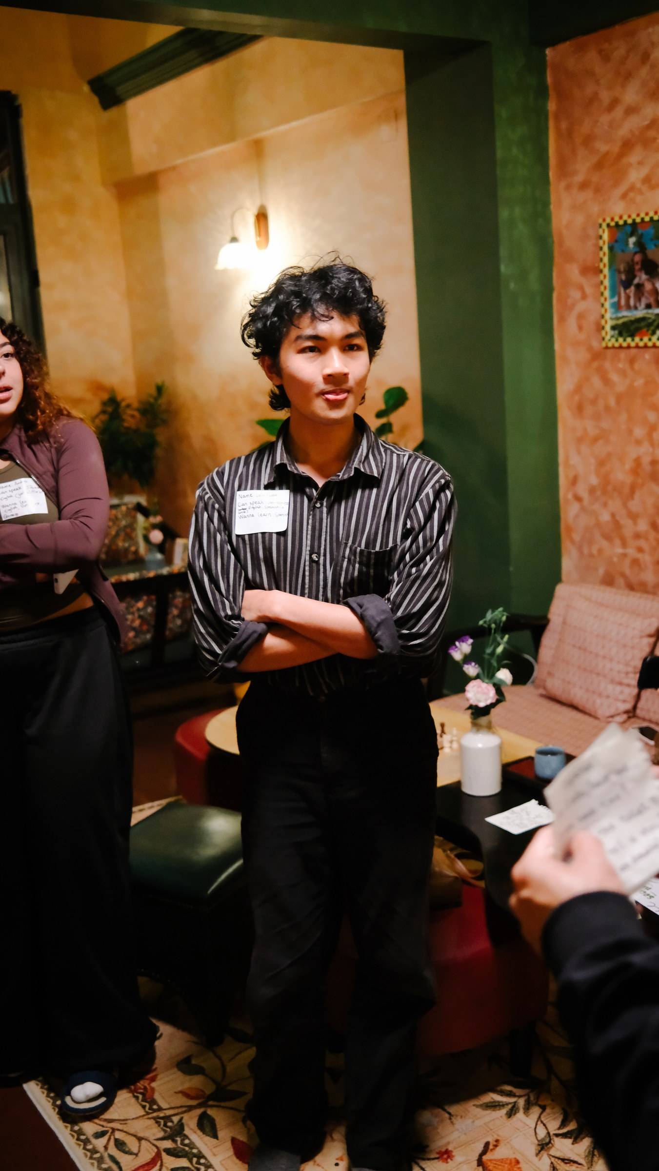 A group of individuals is gathered in a cozy indoor setting with warm lighting and decorative elements typical of Đà Lạt's charming cafes or community spaces.
