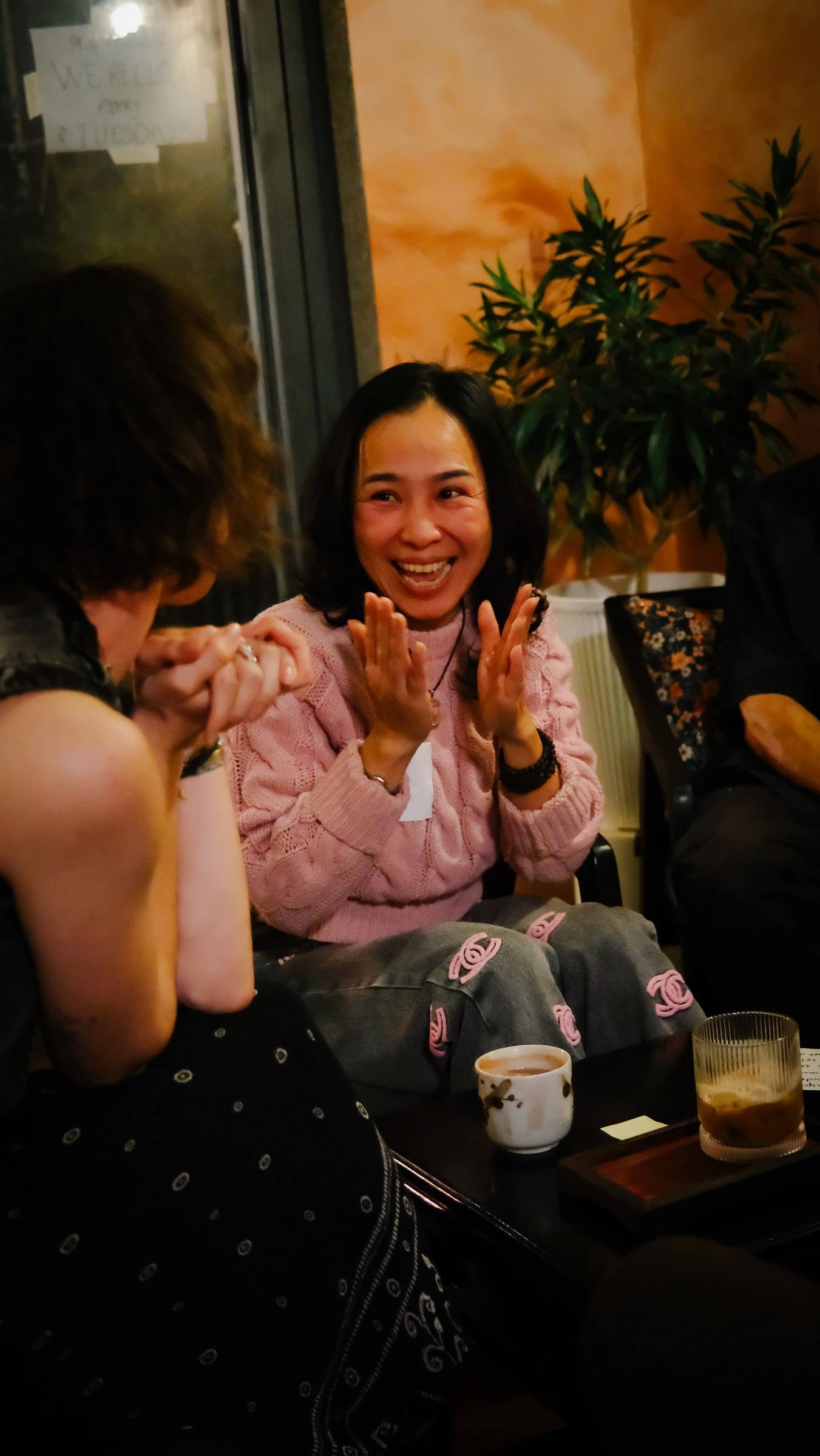 Friends share laughter in a cozy café setting in Đà Lạt, Vietnam, enjoying drinks and casual conversation.