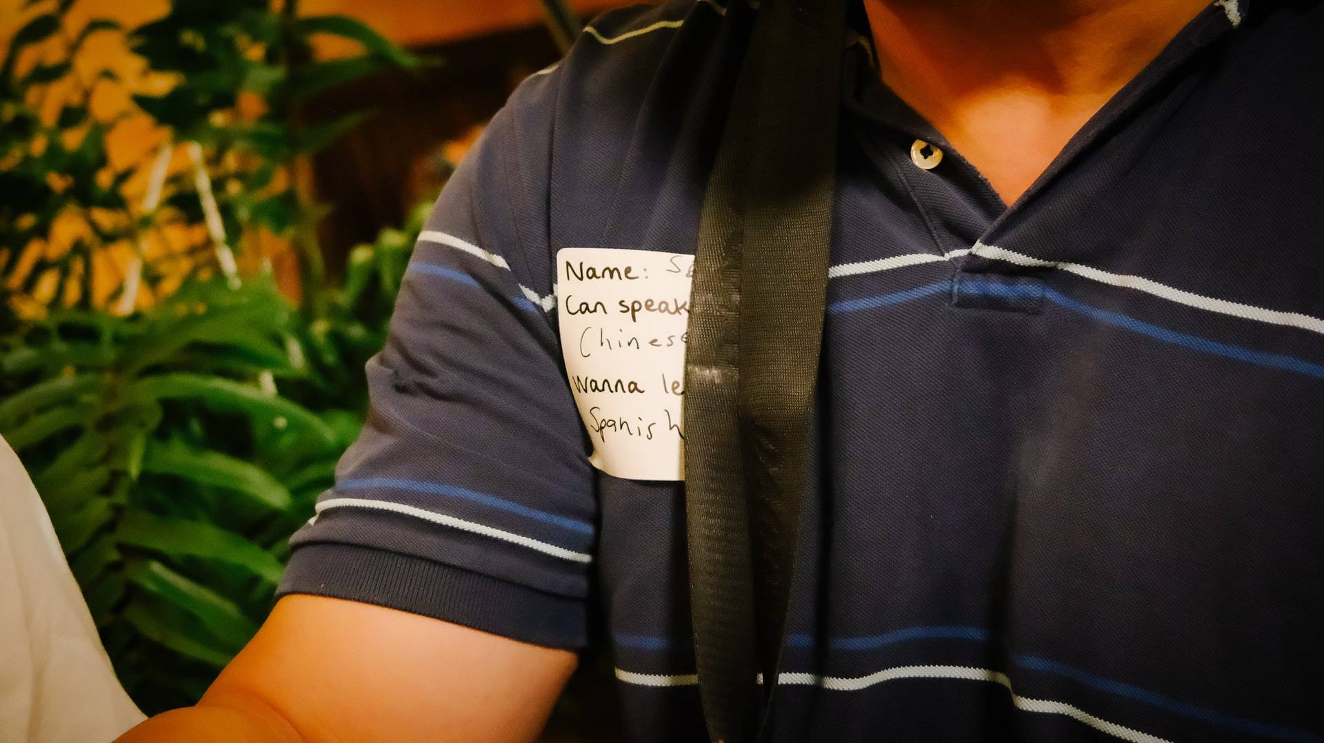 A close-up of a person wearing a name tag that indicates they can speak Chinese and Spanish during an event in Đà Lạt, Vietnam.