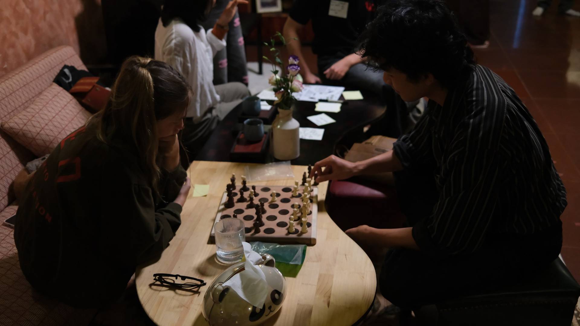 Friends gather in a cozy café in Đà Lạt to enjoy a quiet evening playing chess and sharing drinks.