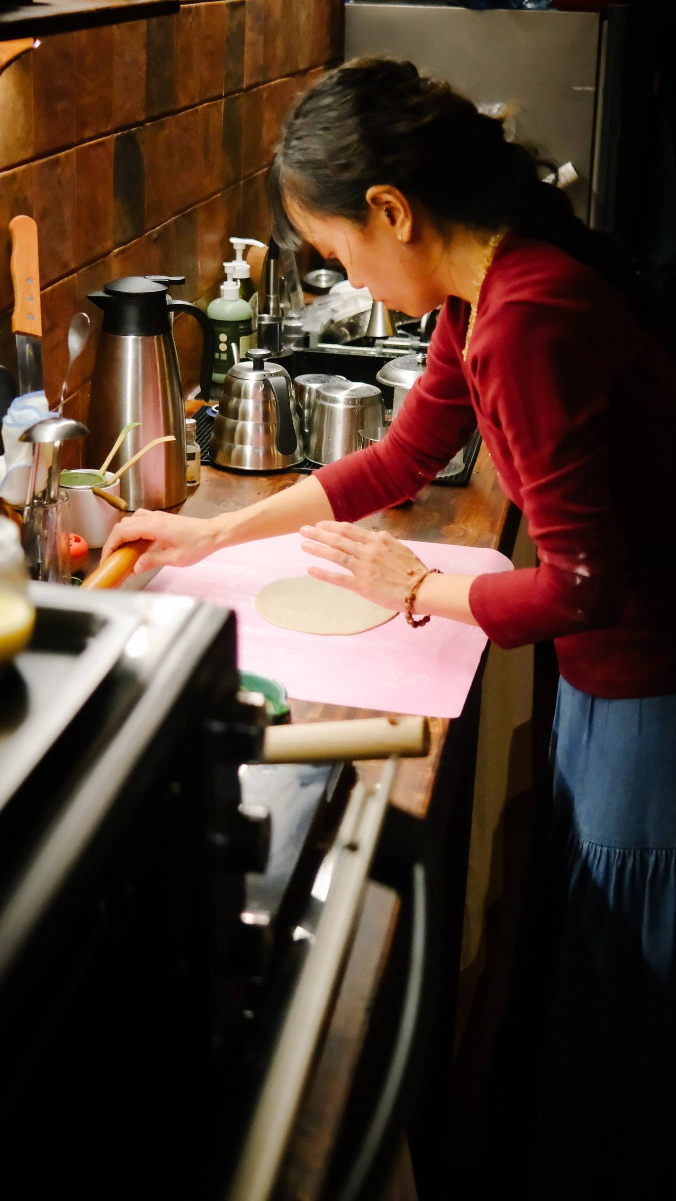 A woman is meticulously preparing a dish in a cozy kitchen setting in Đà Lạt, Vietnam, using traditional cooking techniques.