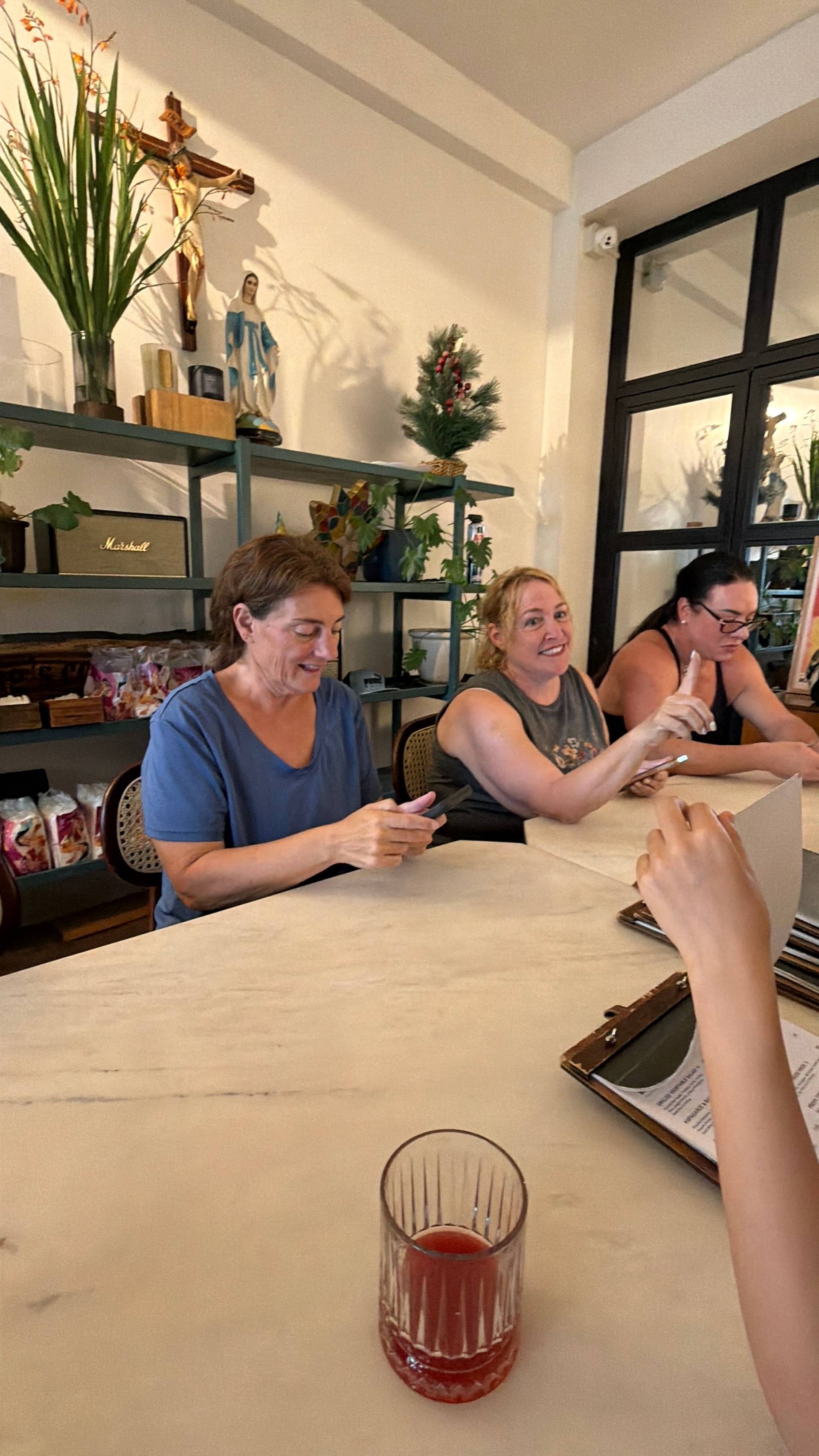 A group of friends enjoys a casual gathering in a cozy café in Đà Lạt, Vietnam, surrounded by religious statues and festive decorations.