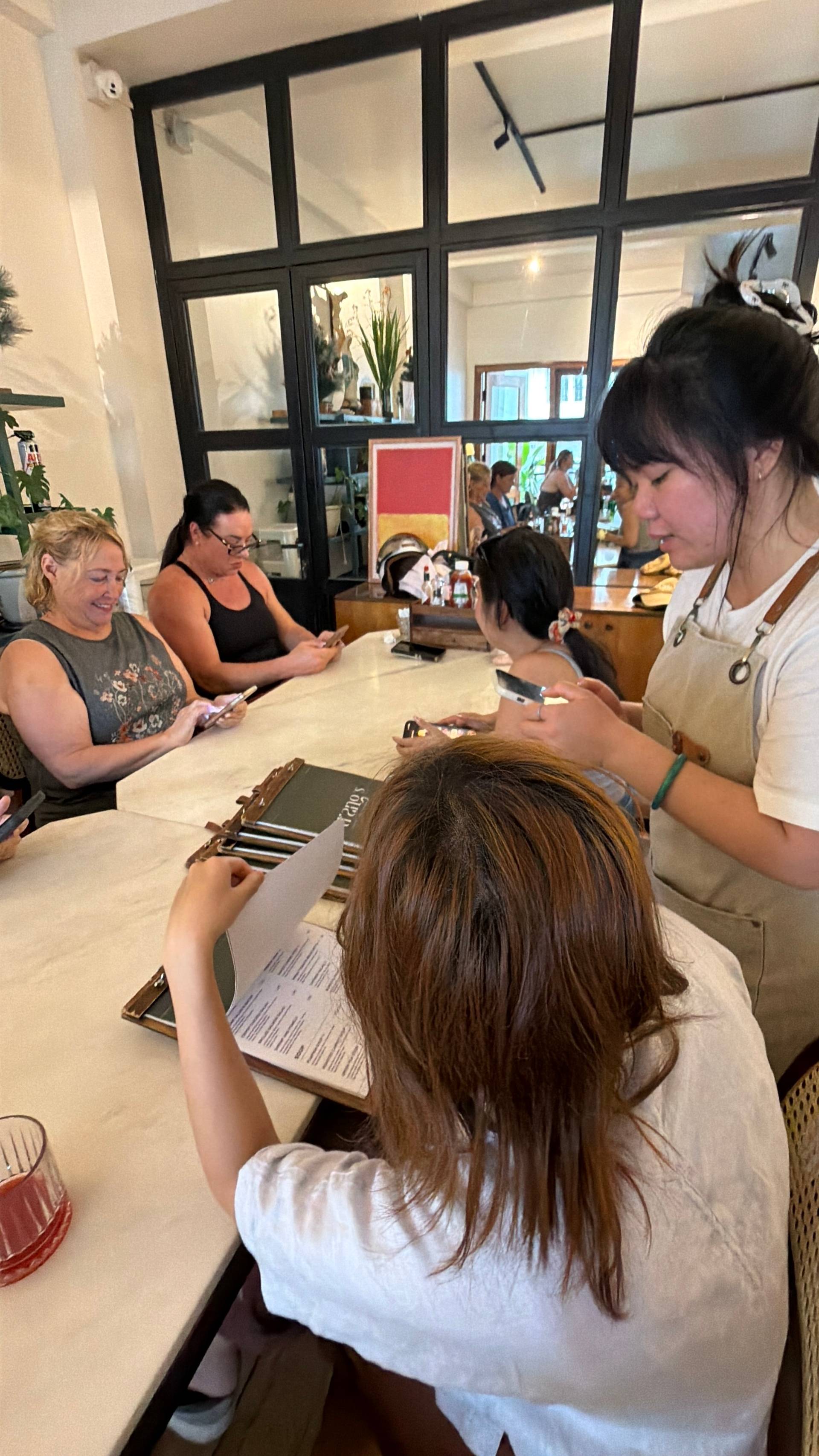 A group of friends enjoys a casual gathering in a cozy café in Đà Lạt, Vietnam, engaging with each other and their phones amidst a relaxed atmosphere.