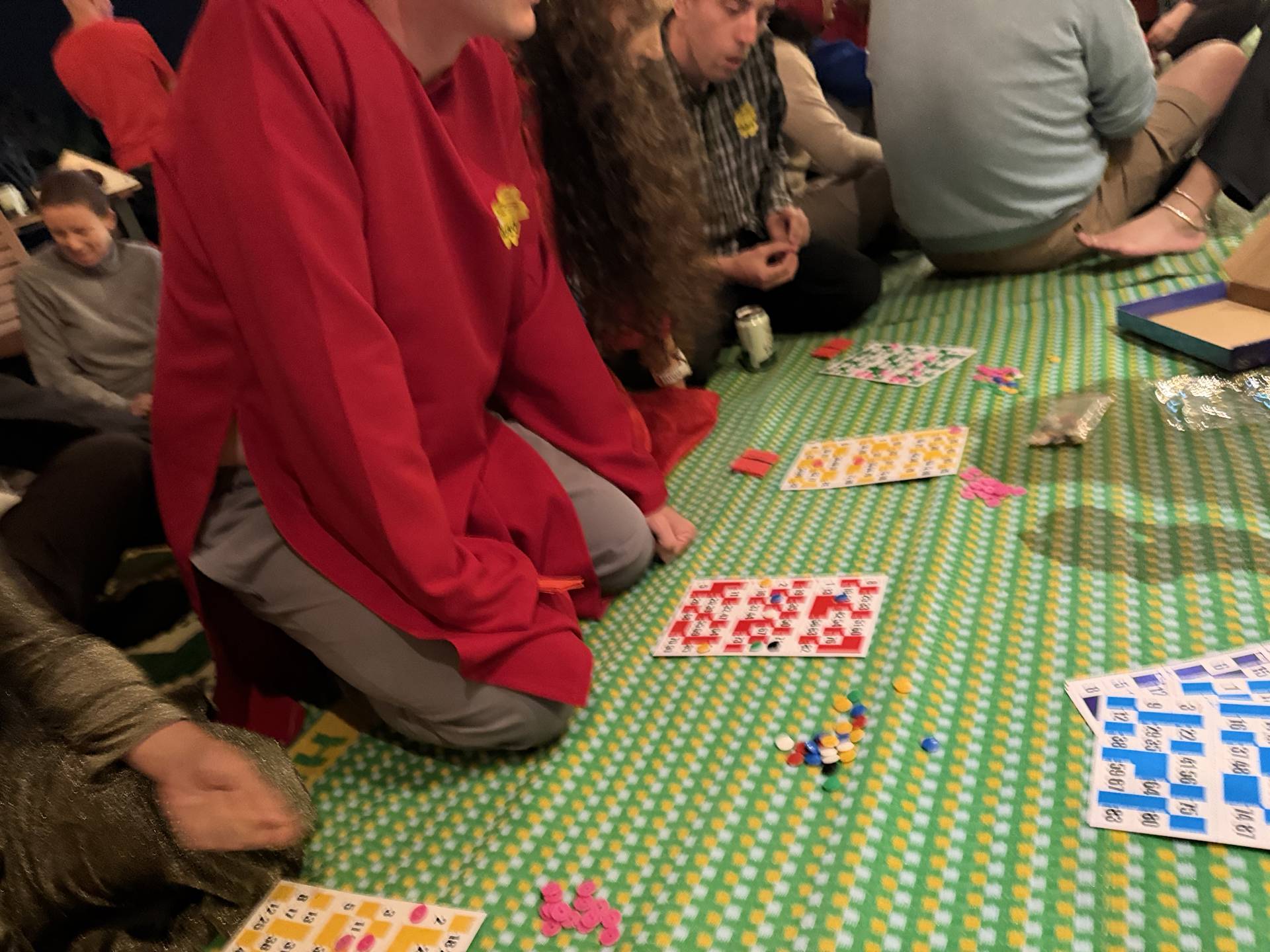 Indoor game night at Đà Lạt event featuring participants playing board games and card games. Green game mat with multiple colorful games creating engaging, interactive celebration atmosphere.