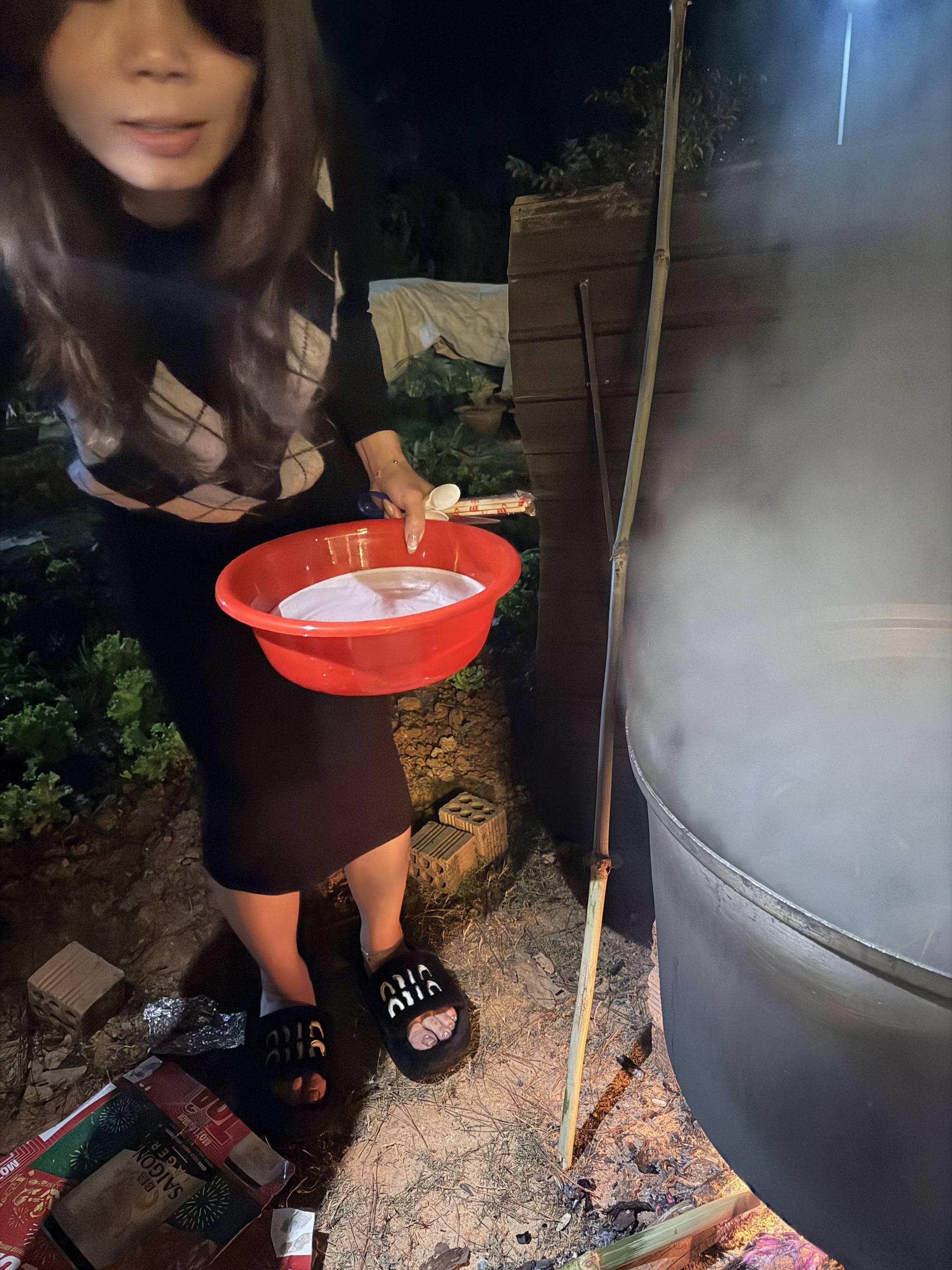 Evening water-based activity or ritual at Đà Lạt event featuring red bowl with water. Intimate nighttime moment capturing traditional or ceremonial element of cultural celebration.