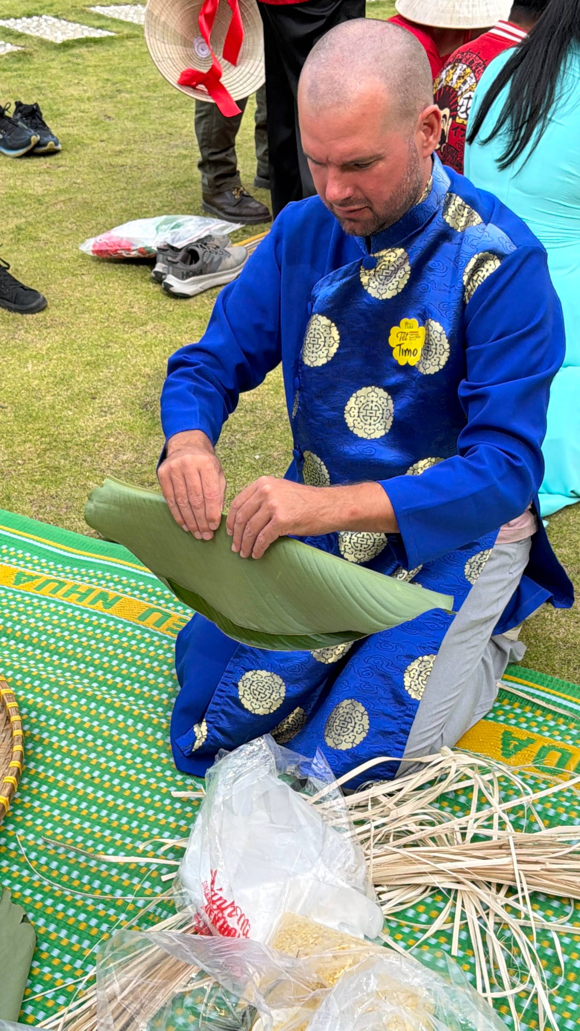 A cultural craft demonstration at a Đà Lạt event on a grass garden with multiple participants wearing traditional conical hats, learning traditional Vietnamese weaving and preparation techniques.
