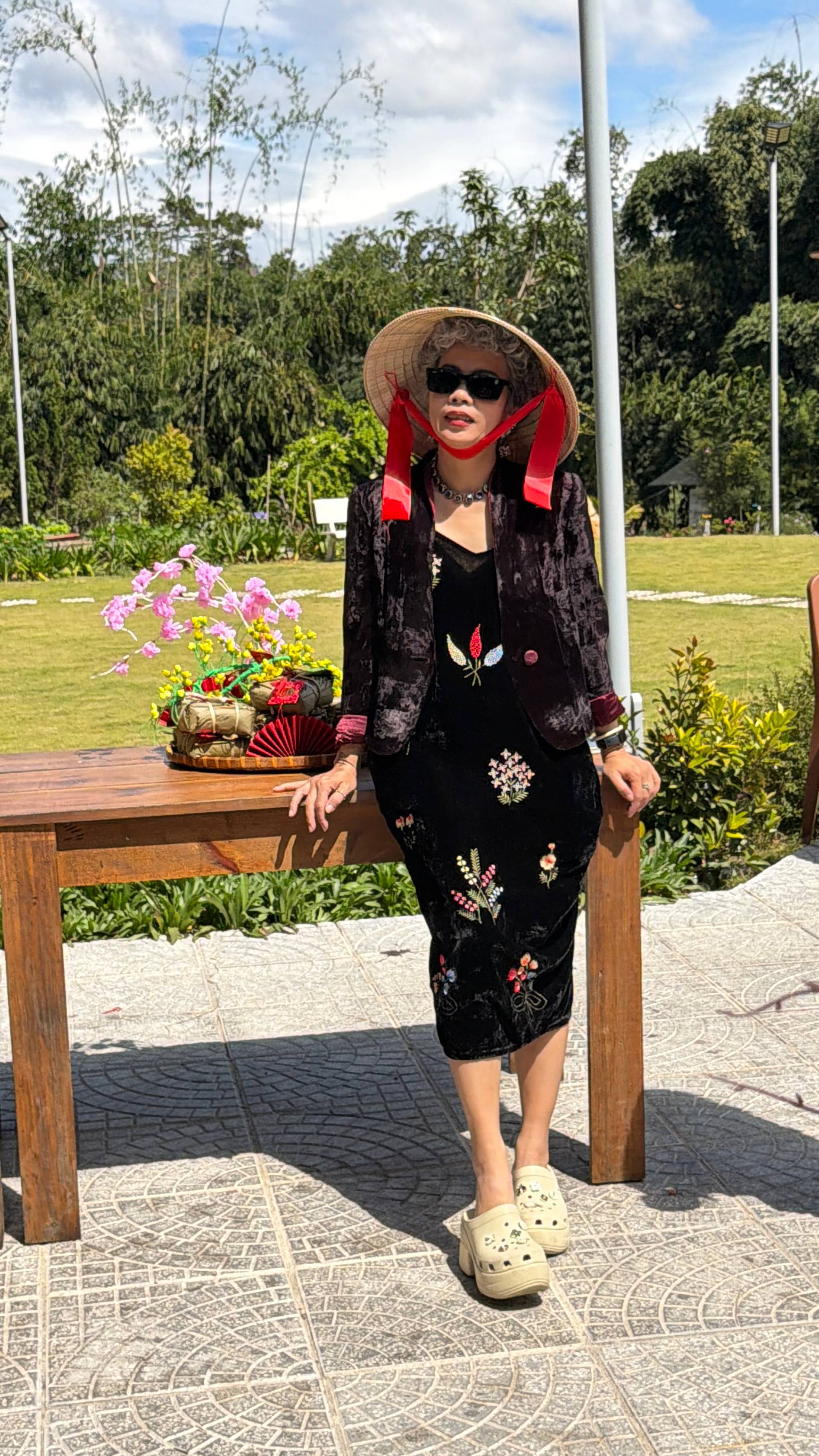 A striking portrait at a Đà Lạt garden venue showcasing traditional Vietnamese costume and Đà Lạt's iconic pine-covered landscape, with theatrical styling and natural highland scenery.