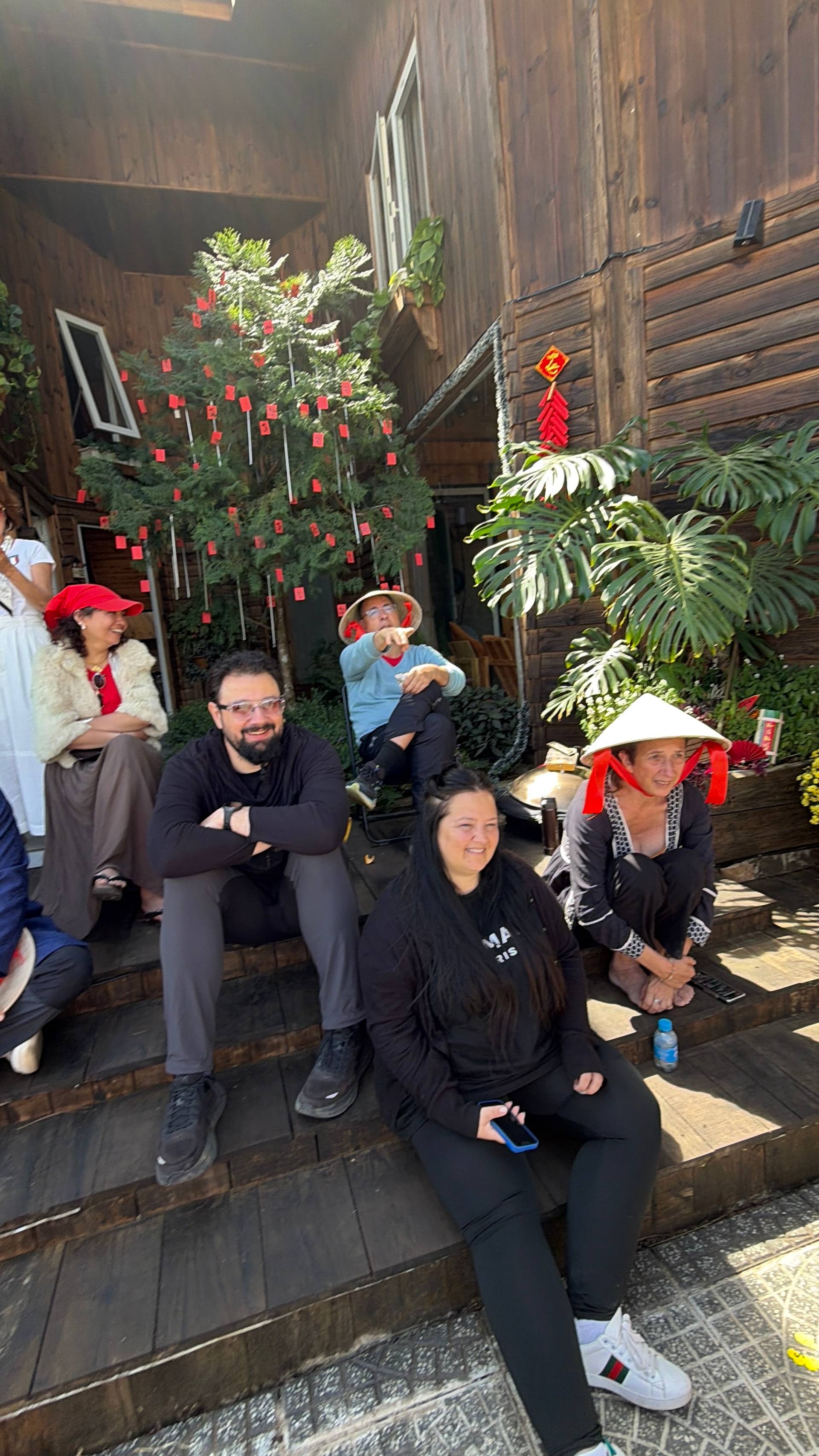 A festive Lunar New Year celebration in Đà Lạt with traditional decorations, conical hats, and communal gathering inside a rustic wooden space decorated with red lanterns.