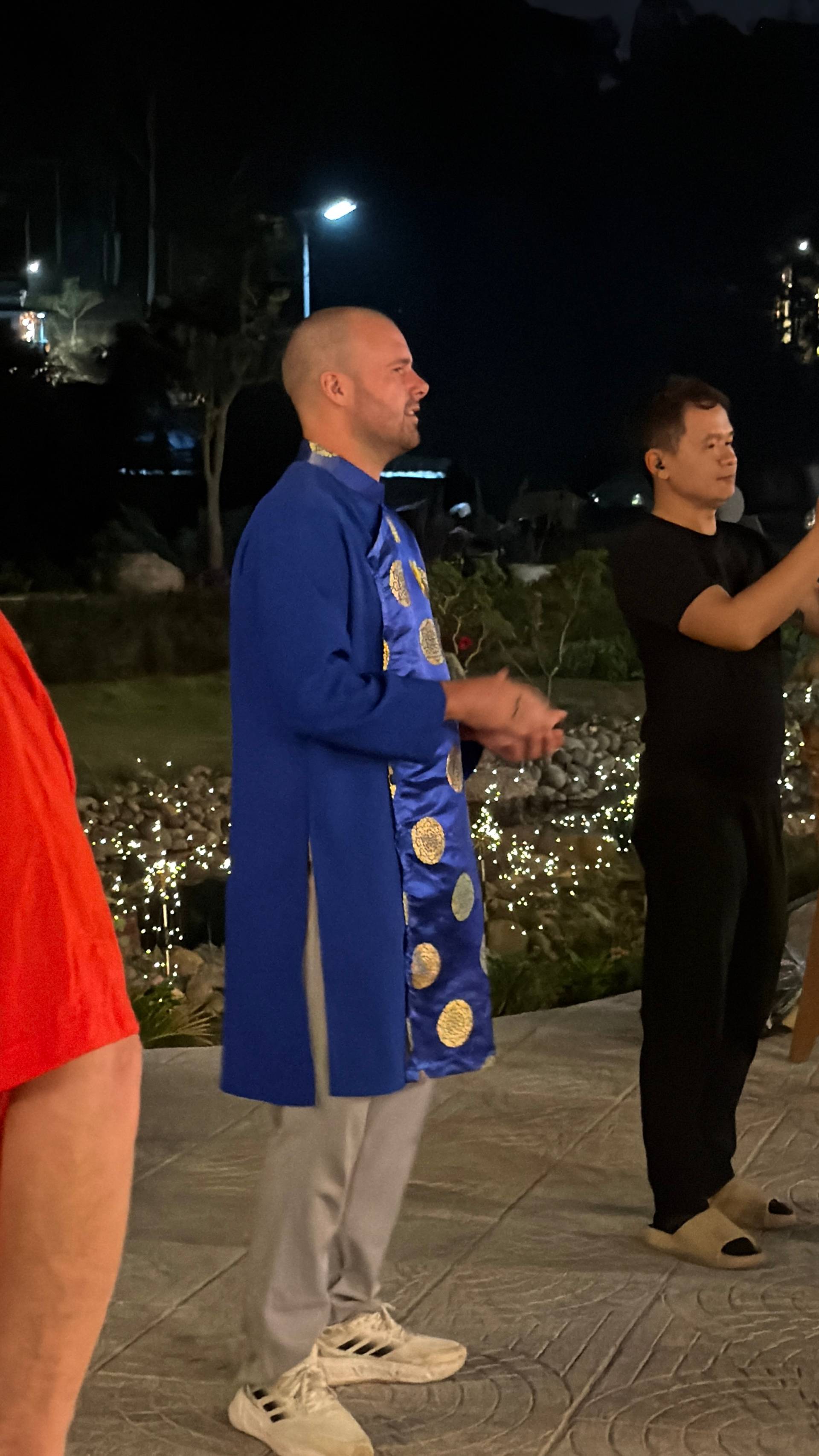 Evening cultural celebration in Đà Lạt featuring traditional Vietnamese áo dài, festive outdoor setting with twinkling lights, flowering plants, and attendees gathered for evening festivities.