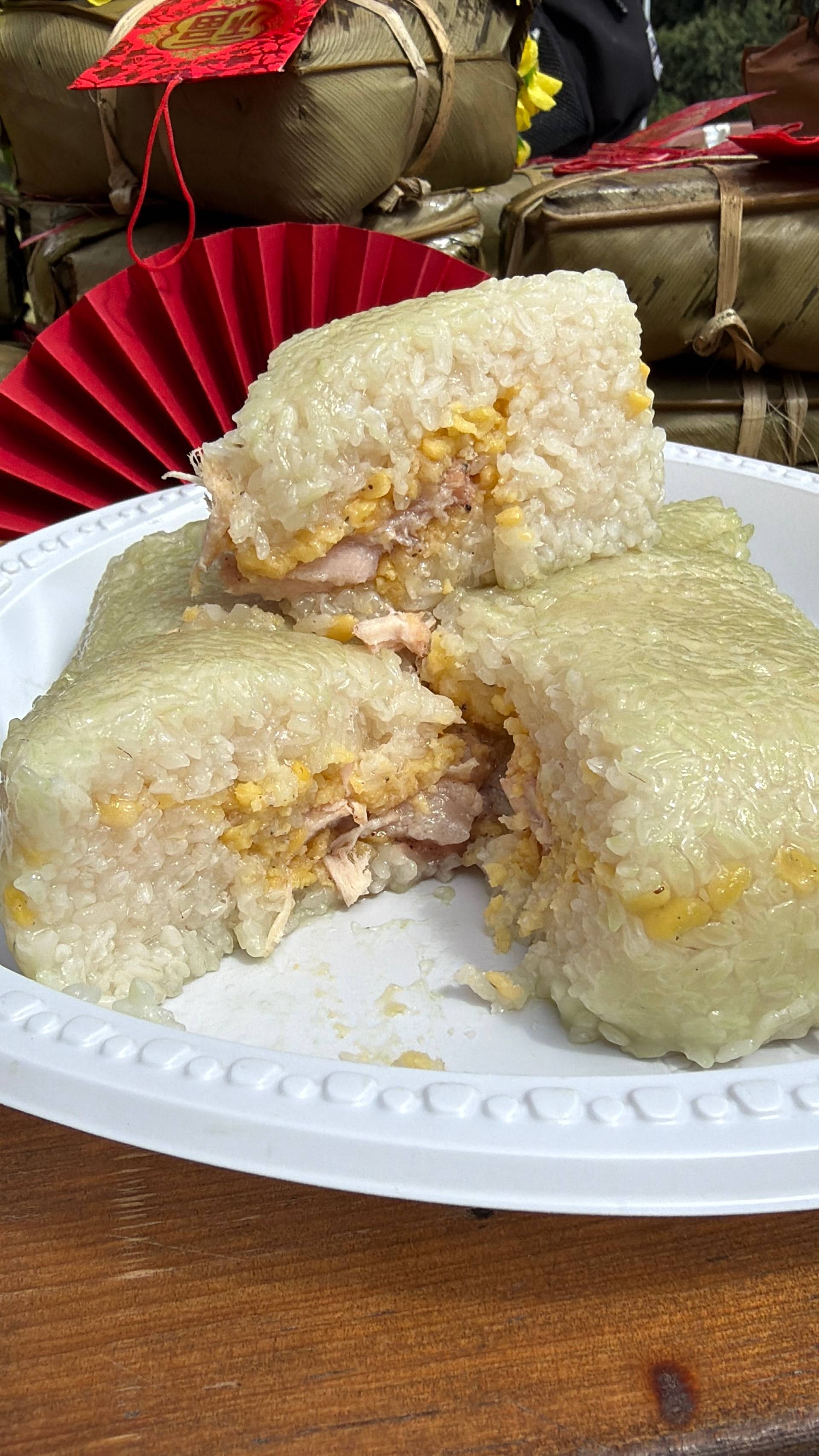Traditional Vietnamese Tết delicacy showcasing bánh chưng rice cakes with green banana leaf wrapping and red decorative ribbon. Close-up food photography highlighting authentic lunar new year culinary traditions.