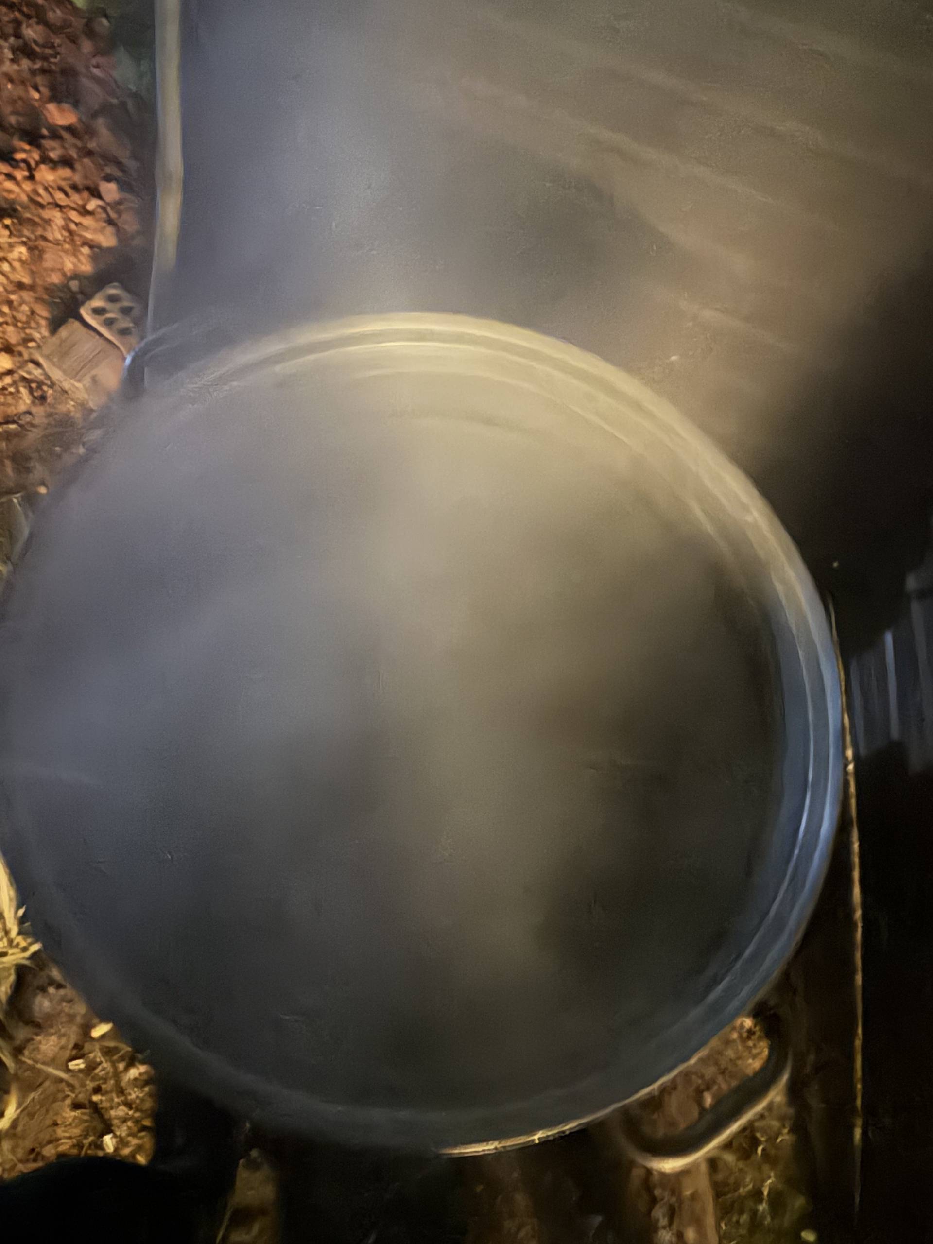 A close-up of a large metal cooking pot or cauldron, suggesting food preparation activities at an event venue.