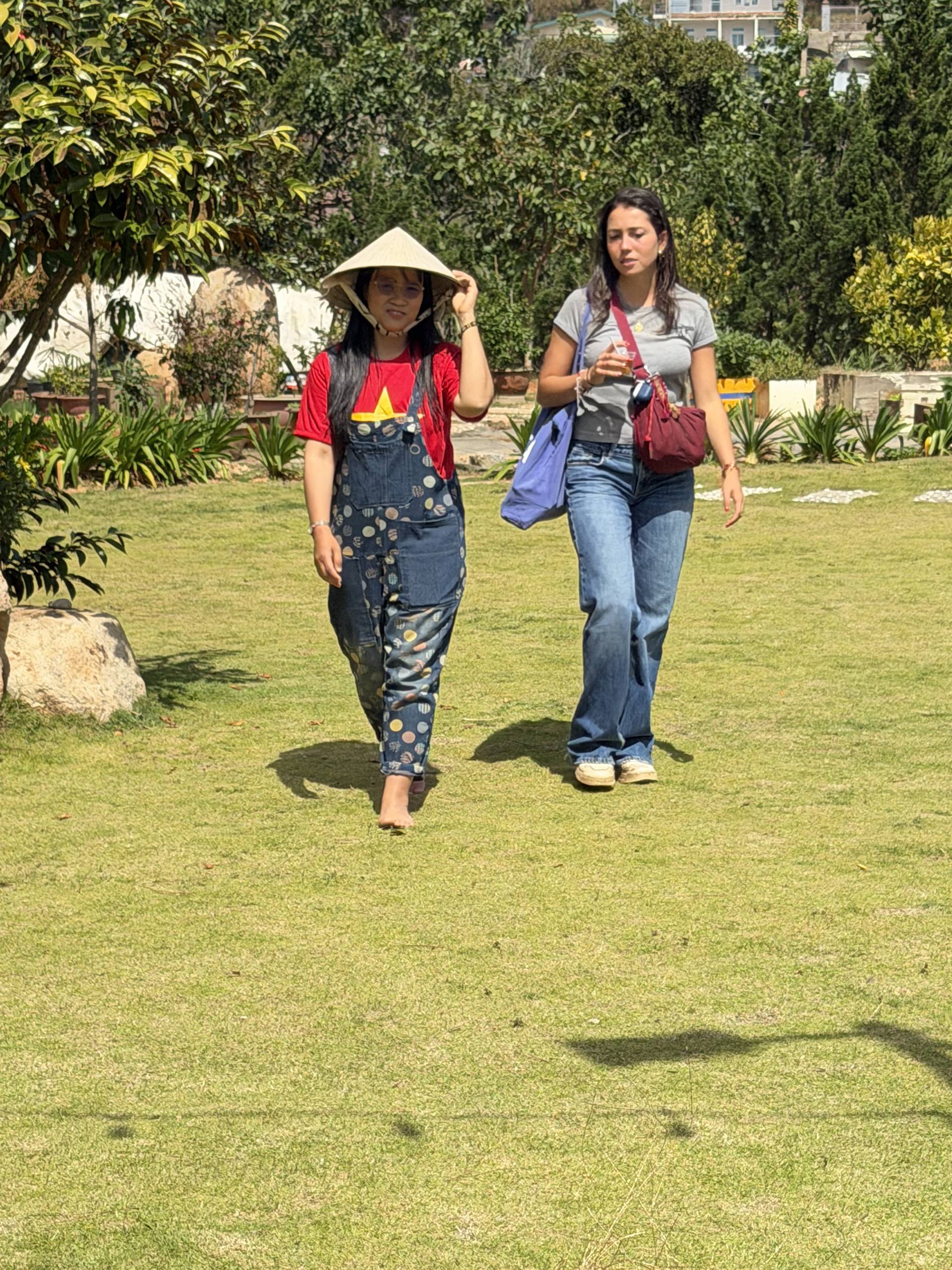 A scenic moment in Đà Lạt's famous pine forests where visitors in traditional dress stroll through the lush highland landscape. The contrast of vibrant cultural attire with Đà Lạt's verdant natural setting captures the unique blend of cultural heritage and natural beauty in Vietnam's mountain destination.