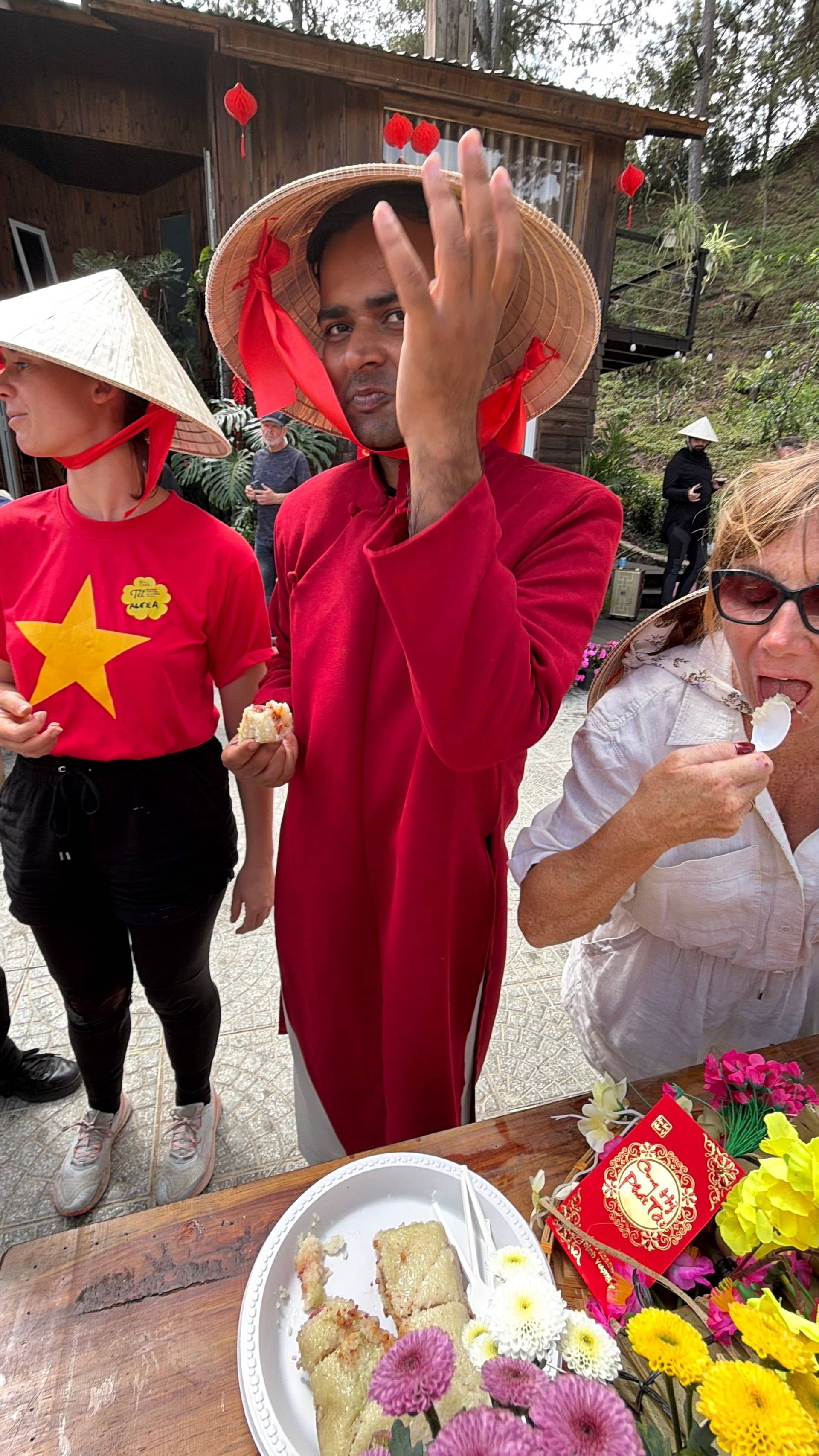 A heartwarming scene in Đà Lạt's heritage gardens captures participants in traditional Vietnamese áo dài and conical hats amidst flowering plants and festival decorations. The intimate cultural celebration showcases Tet traditions in this mountain city's charming garden venues.