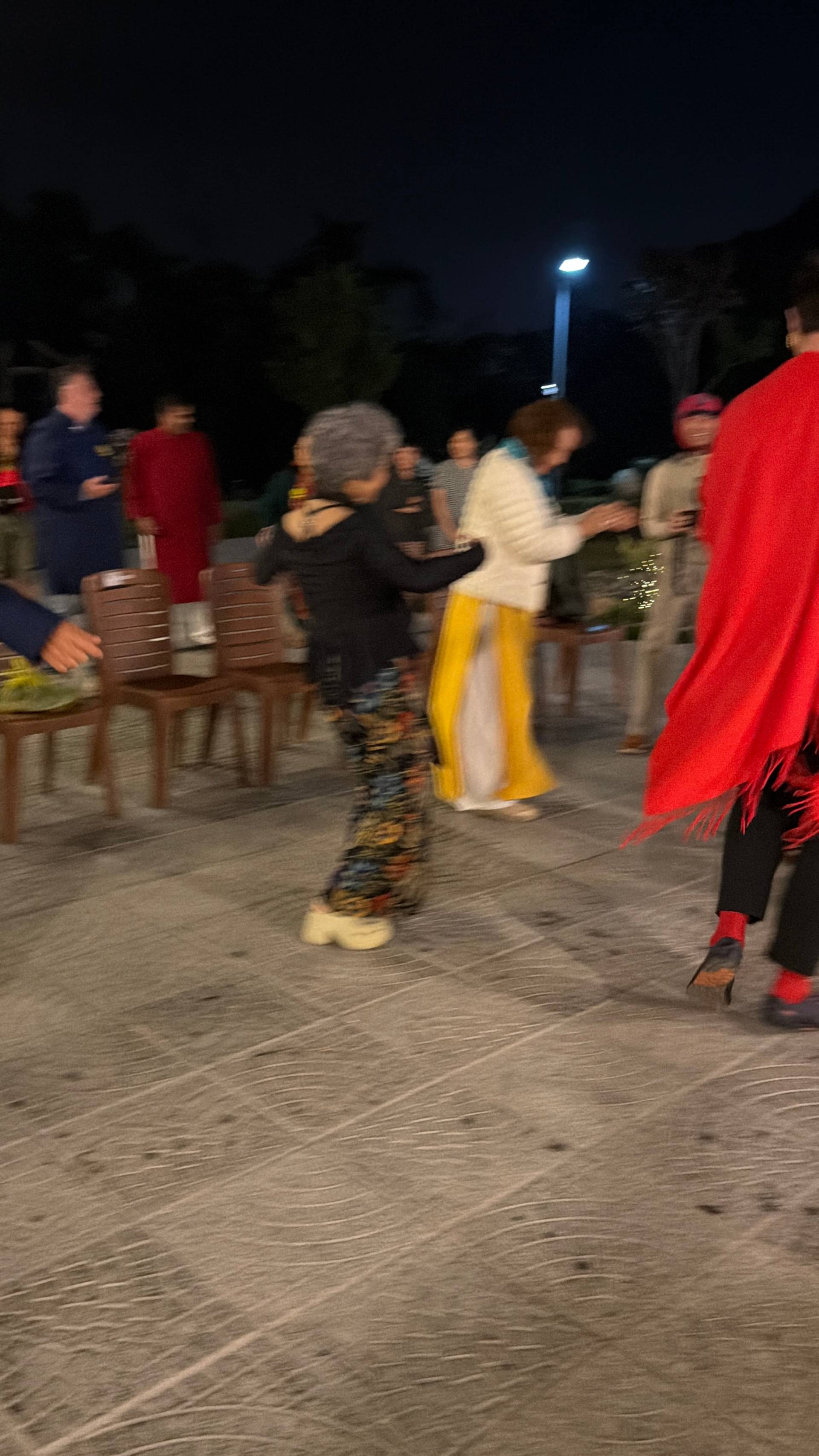 An energetic evening celebration at a Đà Lạt festival captures traditional Vietnamese dancers in colorful áo dài and conical hats under festive lantern lighting. The dynamic motion blur conveys the joyful spirit and cultural vitality of a Lunar New Year nighttime gathering.